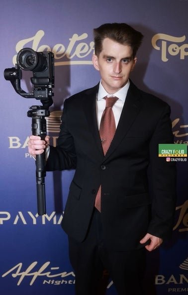 connor dresses in a suit holding a camera