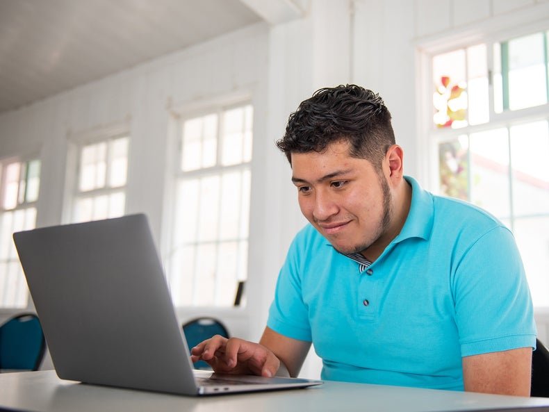 a young man with a blue polo shirt on using a laptop