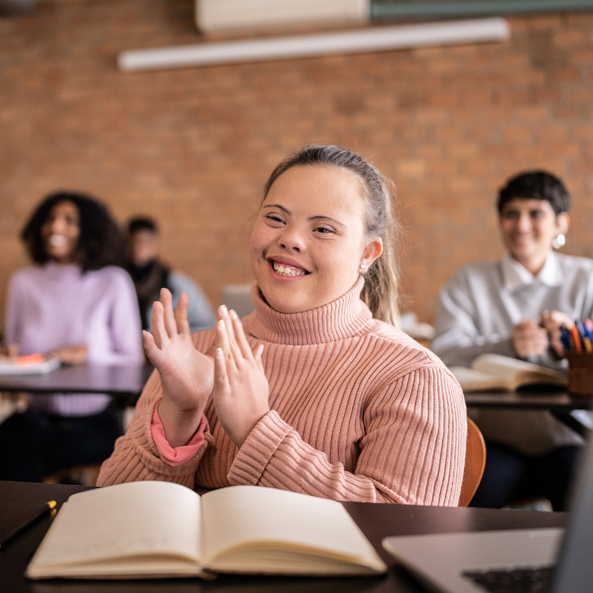A student in a classroom setting clapping at her desk. 