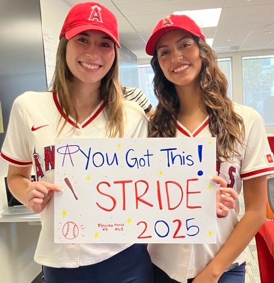 LA Angels Strike Force member holds up a poster that reads, "You Got This! Stride 2025."