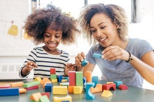 Two people are happily playing with colorful building blocks on a table.
