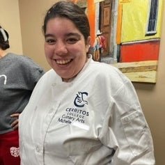 Person in a Cerritos College Culinary Arts chef jacket smiling at the camera.