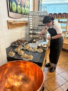 Makena wearing a black apron working at Rocky Mountain Chocolate Factory.