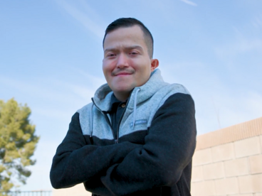 Eddie standing with his arms crossed and the blue sky in the background
