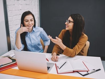 two young women working in front of a laptop