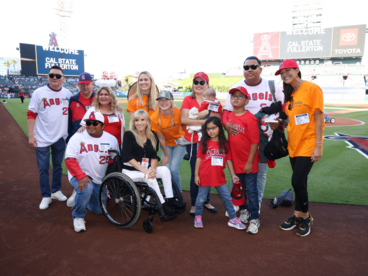 Group of people posing for a photo on a baseball field. Several individuals are wearing Los Angeles Angels apparel.