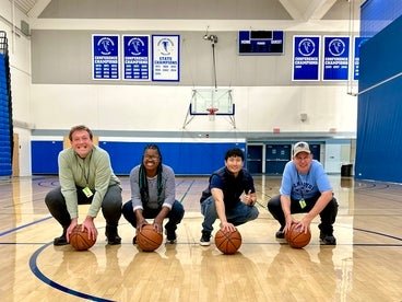 Individuals from Easterseals Adult Day Services holding basketballs in a gym