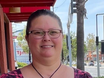 gina standing smiling with a butterfly necklace on