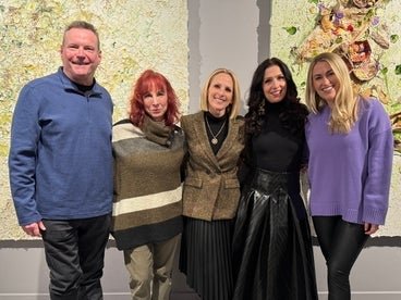 A group photo of five individuals standing in front of art pieces at the Sundance Festival. 
