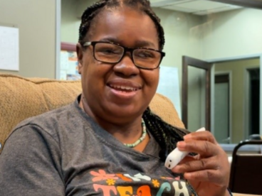 Participant Orina showing off her C-Pen device and smiling 