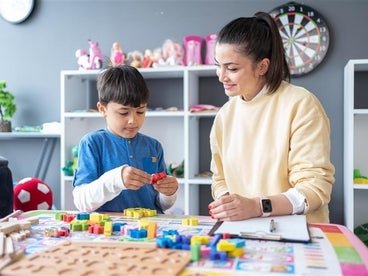 young boy playing with blocks and adult woman