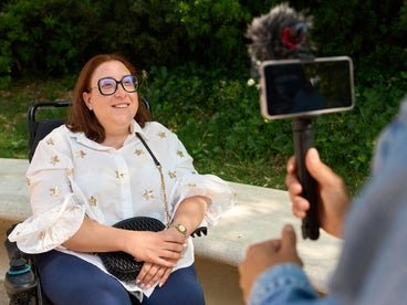 woman in wheelchair speaking into the camera and mic