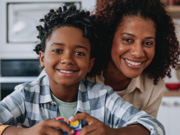 A toddler and his mother sitting at a table while his plays with his sensory toys.