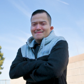 Eddie standing with his arms crossed and the blue sky in the background