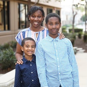 mother standing behind her two young sons
