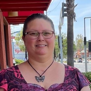 gina standing smiling with a butterfly necklace on