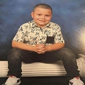 junior sitting down on a pillar smiling