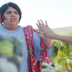 A photo of Ady high-fiving her family member and wearing noise cancelling headphones.
