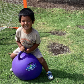 Jameson bouncing on a purple ball in a backyard setting. 