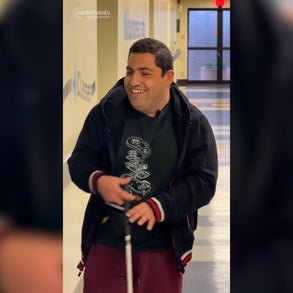 Alfred smiling while walking down a school corridor. 