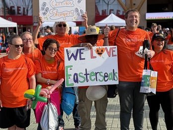 group of people wearing orange shirts holding up we love easterseals sign