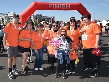 group of people smiling wearing orange shirts and medals