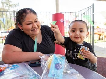 mother looking at young son holding apple juice box