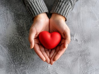 Hands holding a heart shaped red rock
