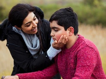 women holding face of young boy