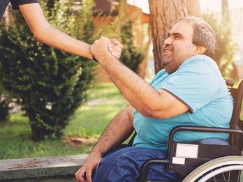 man in wheelchair being supported
