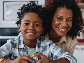 A toddler and his mother sitting at a table while his plays with his sensory toys.