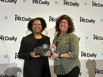 Kim Cohn and Shelley Ginsburb Brown accepting the PR Daily award in front of a PR Daily step and repeat