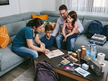 A family of four is gathered around a coffee table in a living room, looking at papers and engaging in a discussion. 