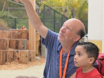  a man pointing with a child looking up in that direction