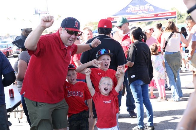 A dad and his three sons wearing Angels gear playing games at the tailgate party