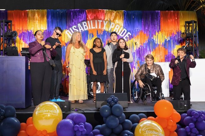 Cast members from Easterseals PSA campaign on stage with Nic Novicki as MC on the right and a ASL interpreter on the left