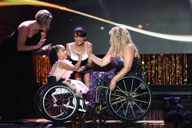 Four individuals on stage during an award ceremony engaging in high fives. 