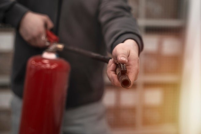 An individual holding a fire extinguisher, with the nozzle directed forward, ready for use.