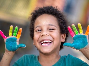 child holding painted hands up