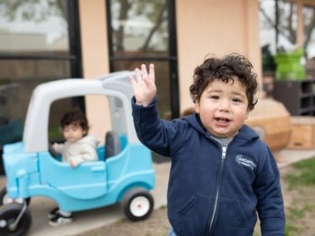 toddler boy waving at camera