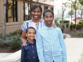 mother standing behind her two young sons