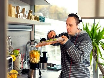 young man wearing headphones making a smoothie