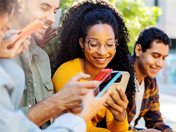 people sitting down using their phones smiling at their screen