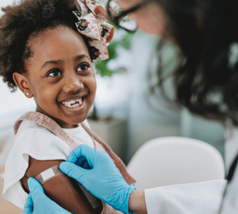 A doctor administering a shot to a young girl in a medical office. 