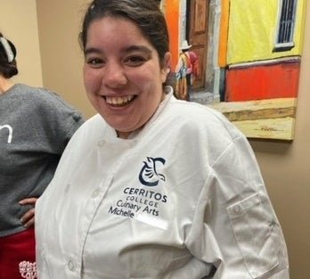 Person in a Cerritos College Culinary Arts chef jacket smiling at the camera.