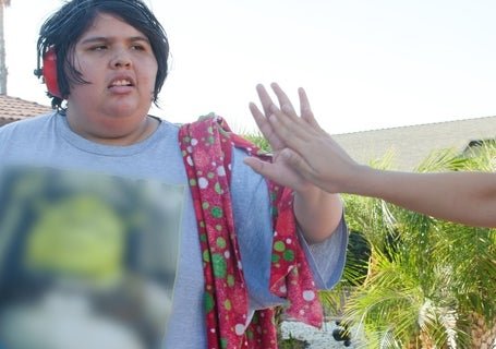 A photo of Ady high-fiving her family member and wearing noise cancelling headphones.